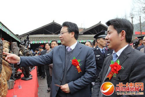 芦山县委书记范继跃(右一)和县委副书记、县长王华(左一)参观民俗节根雕精品